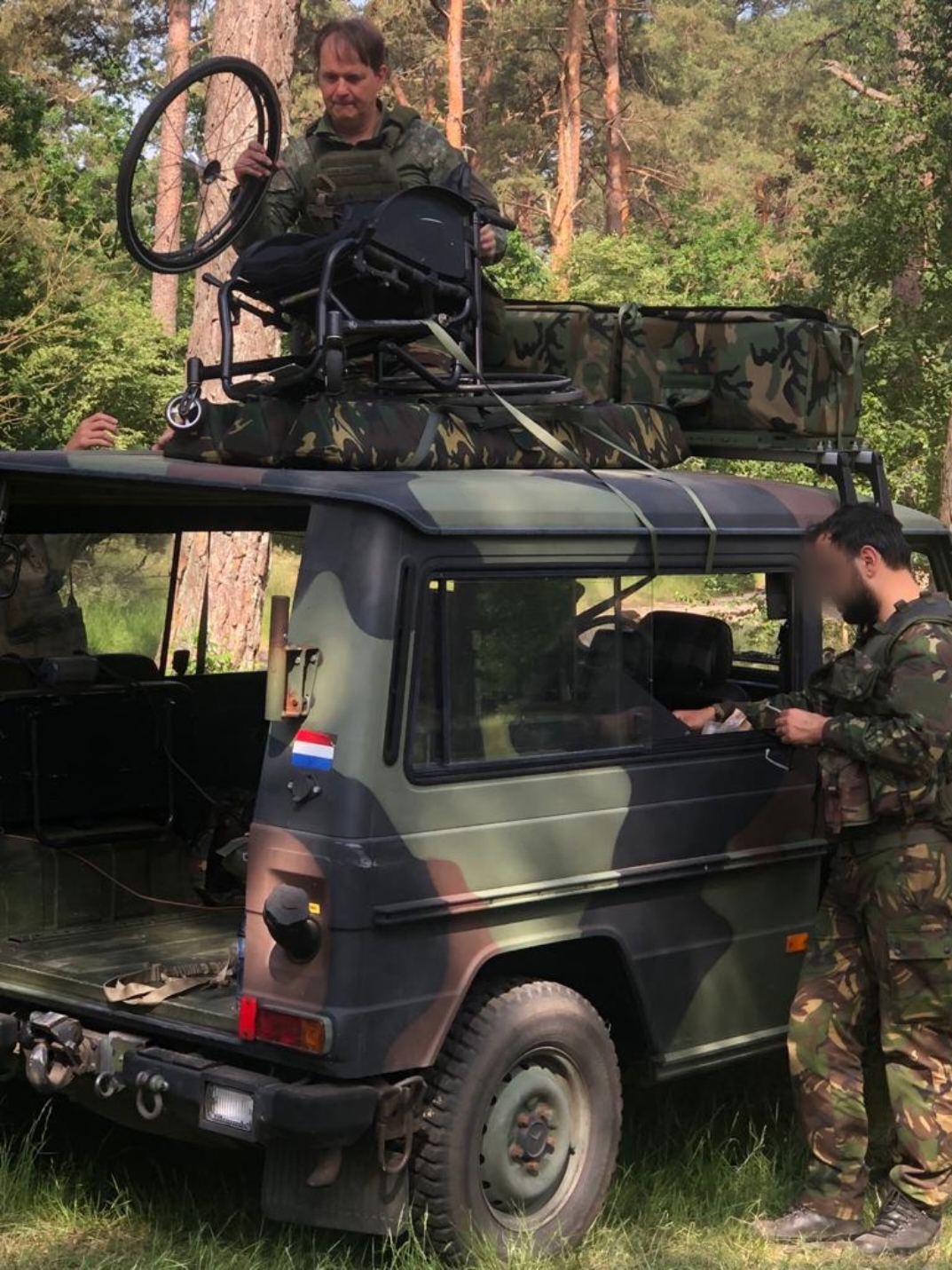 Funda's rolstoel wordt op haar aanwijzingen op een militaire jeep geplaatst.